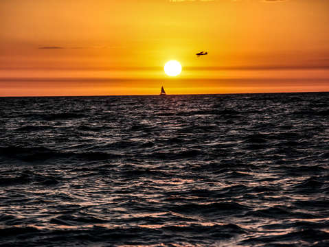 Sailboat and airplane at sunset