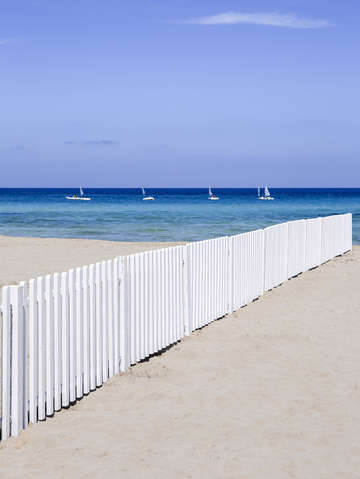 Fence on beach with boats