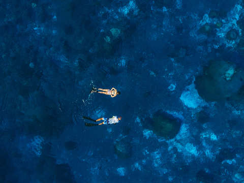 Aerial photo of snorkelers in a cobalt blue sea