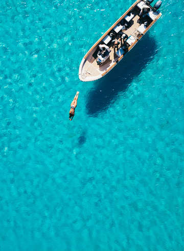 Aerial view of a diver in a sapphire blue sea