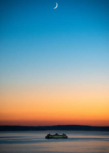 Ferry departs Seattle at sunset beneath the crescent moon and Venus