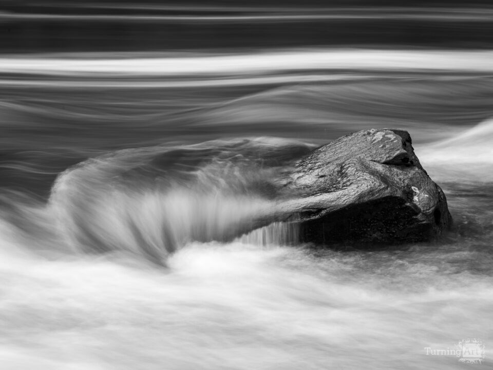 Monochrome rock withstands the power of the river